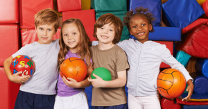 4 young kids holding volleyballs|A boy playing at day camp