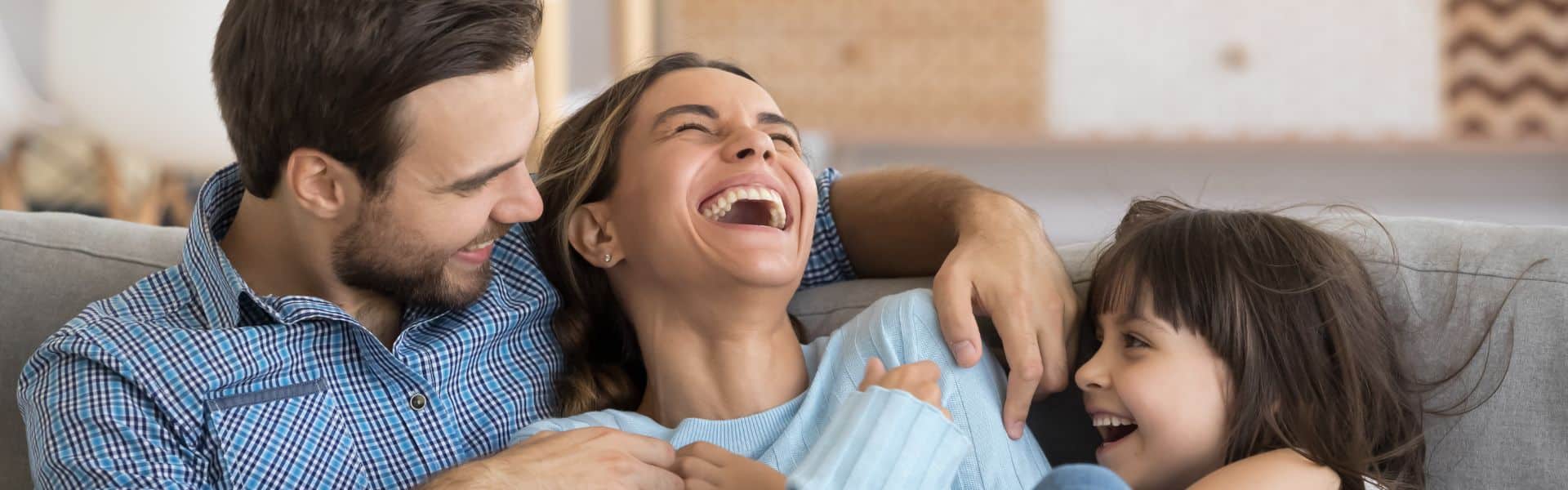 Father and Mother along with child on couch laughing together